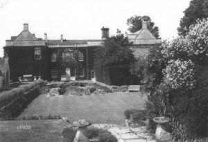 1928 view of Dauntsey House's east face covered with ivy, and an ornamental garden and reflecting pool